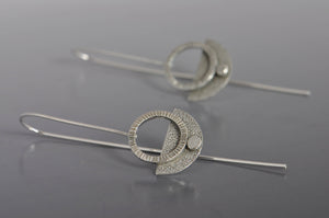 chiseled and pebbly textured silver dangle earrings on long silver ear wires
